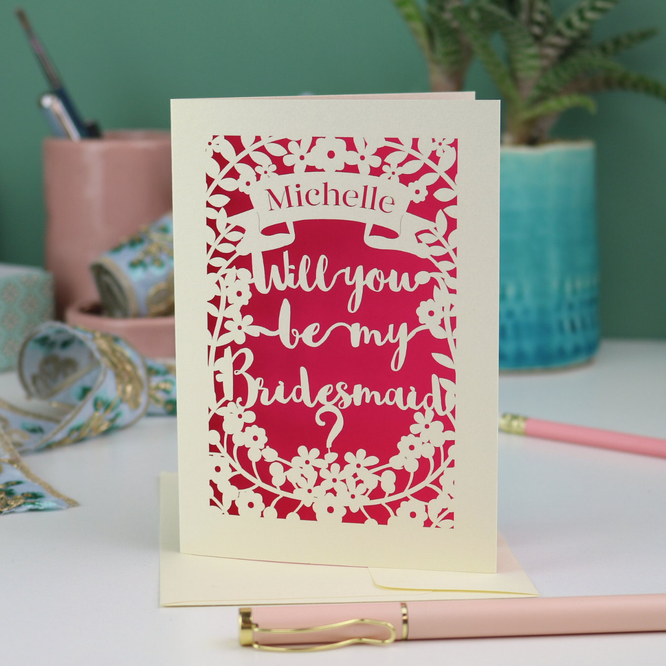 Laser cut Card with 'Will you be my Bridesmaid?' text on a desk with stationery items.