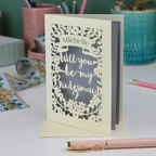 Laser-cut card asking 'Will you be my bridesmaid?' on a desk with stationery items.