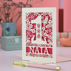 Decorative laser cut 1st birthday card with cut-out design and 'Naia' text on a pink background