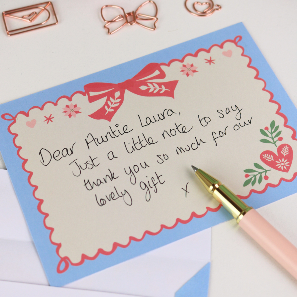 Handwritten letter on a decorative note card with a pen and stationery items.