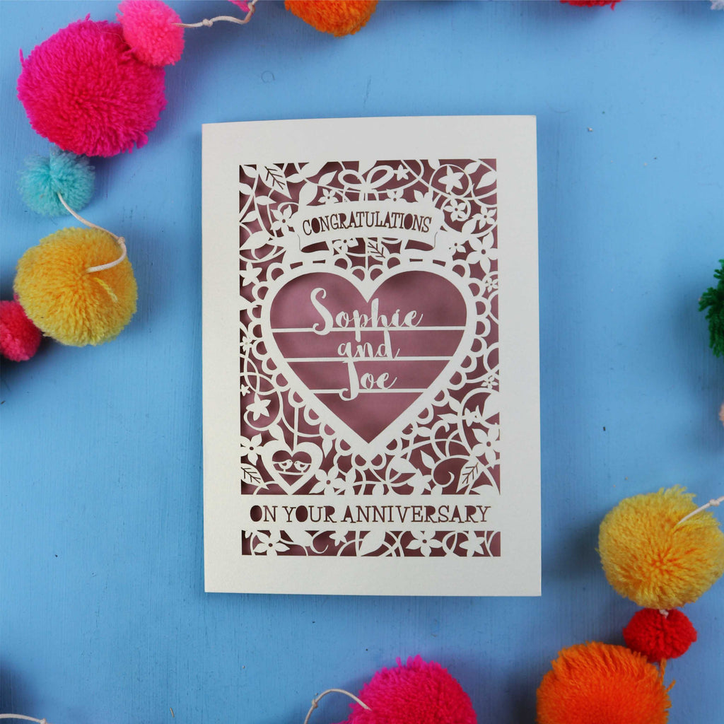 Personalised papercut wedding anniversary card with decorative heart design on a blue background with colourful pom-poms.