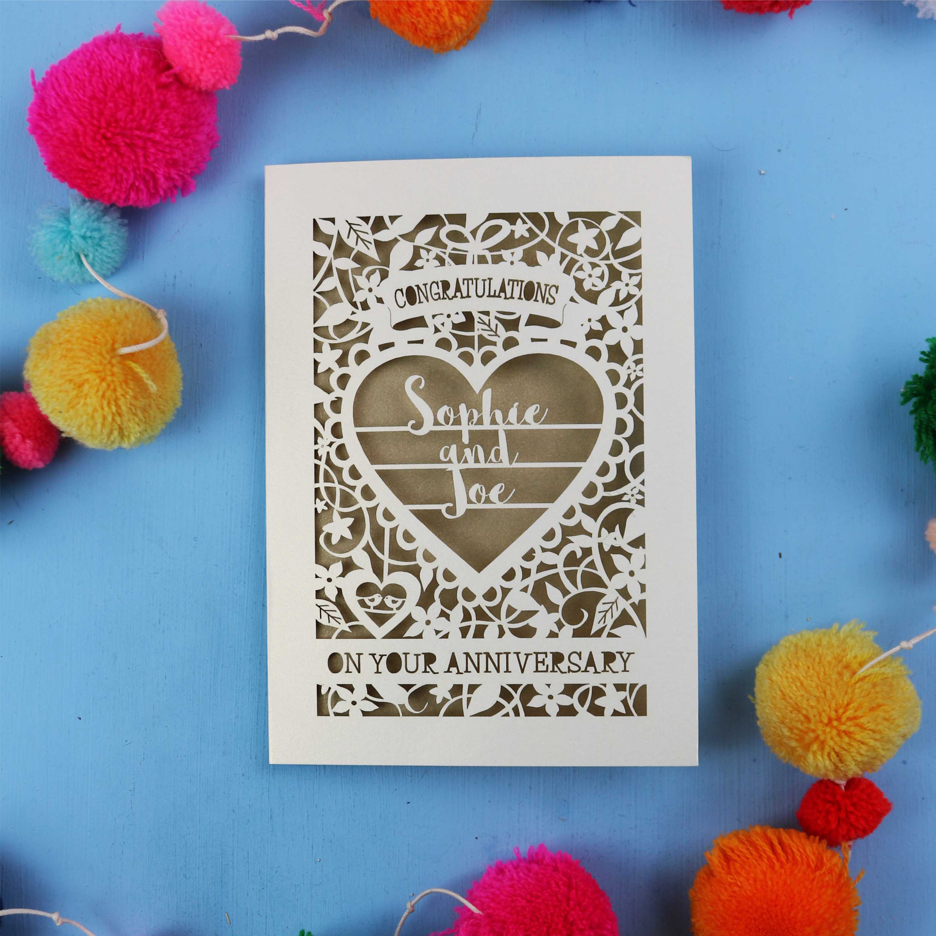 Personalised golden wedding anniversary card with decorative heart design on a blue background with colourful pom-poms.