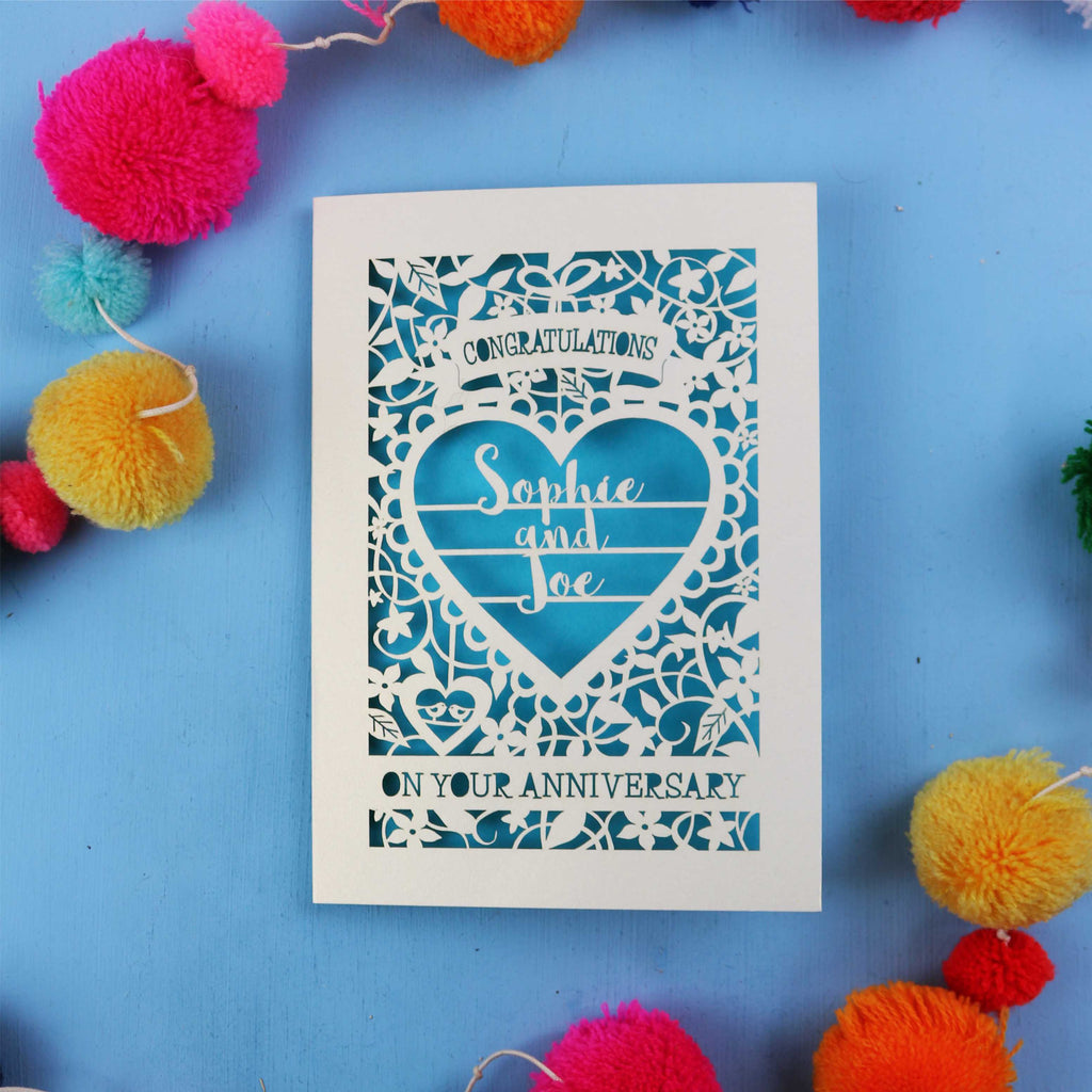 Personalised wedding anniversary card with decorative heart design on a blue background with colourful pom-poms.