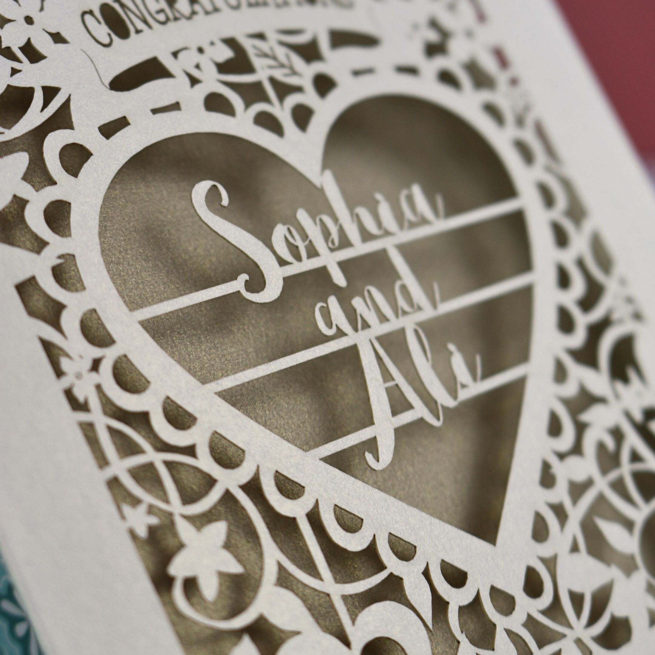 Laser-cut heart-shaped card with 'Sophia and Ali' text on a decorative background
