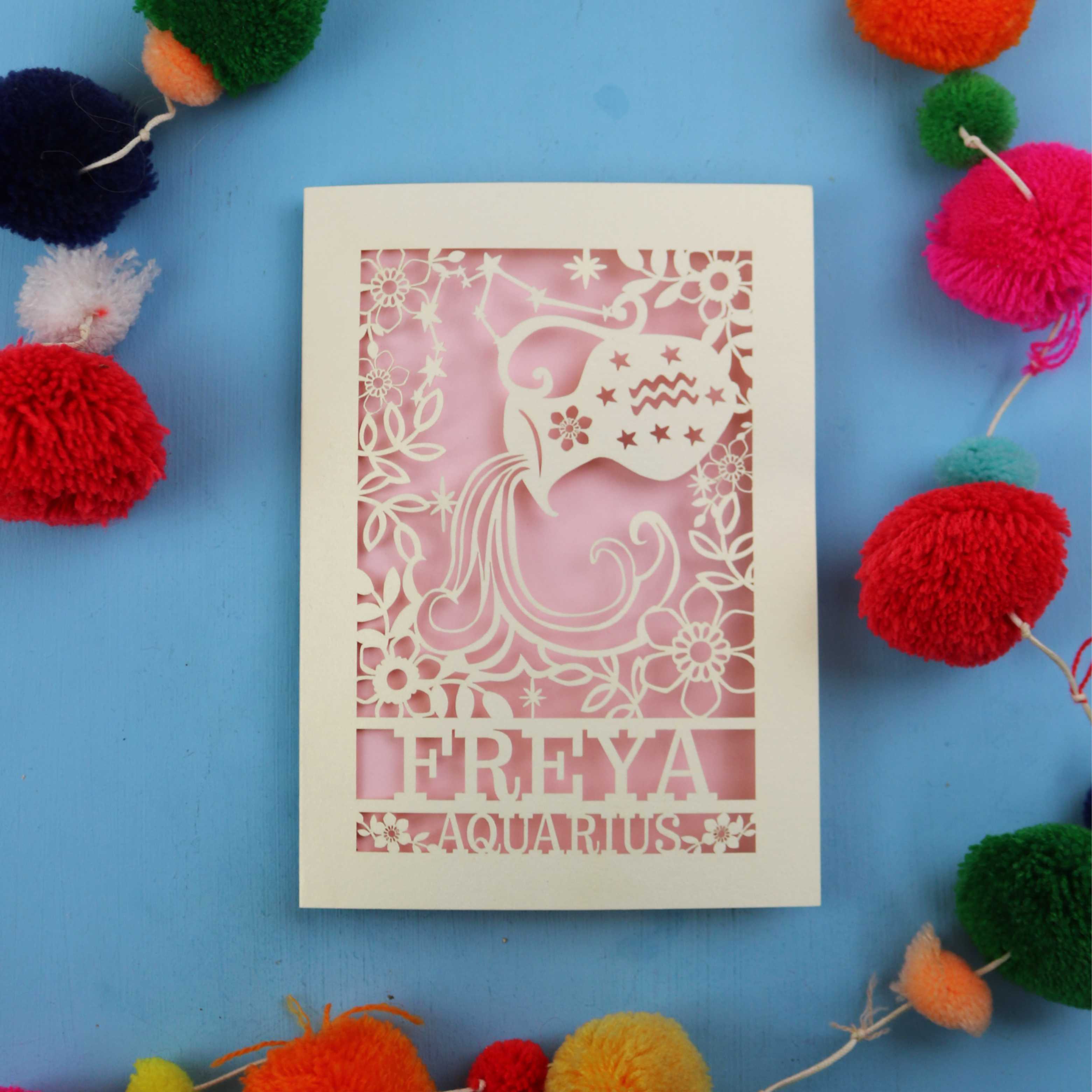 Decorative Aquarius Birthday card with 'FREYA AQUARIUS' design on a blue background with colourful pom-poms.