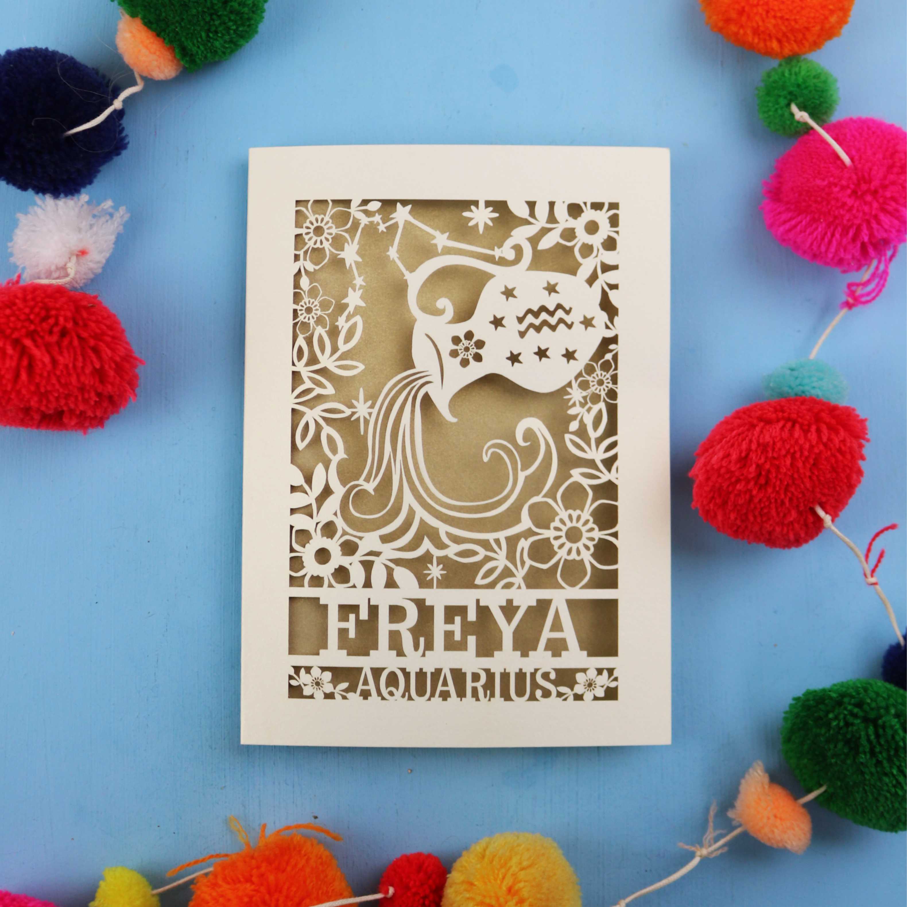 Decorative Aquarius Birthday card with 'FREYA AQUARIUS' design on a blue background with colourful pom-poms.