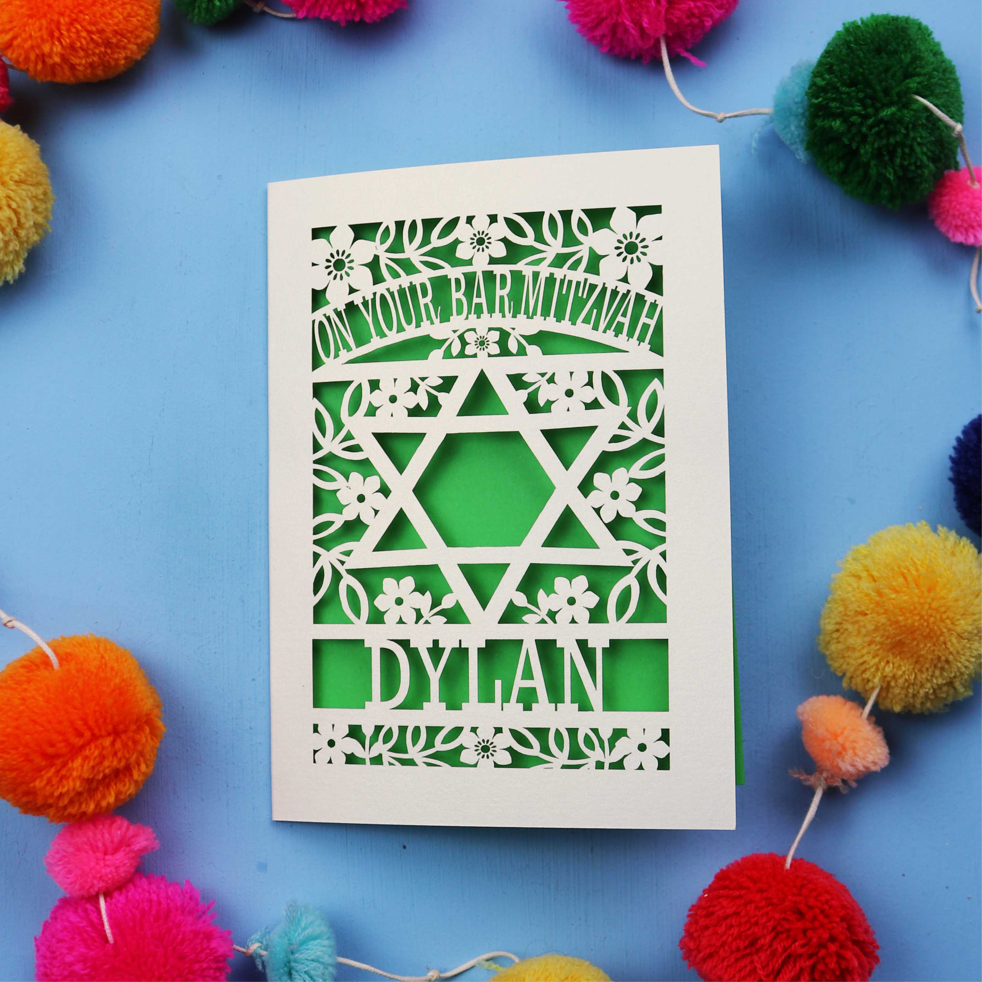 Bar Mitzvah Card with Star of David design and name 'Dylan' on a blue background with colourful pom-poms.