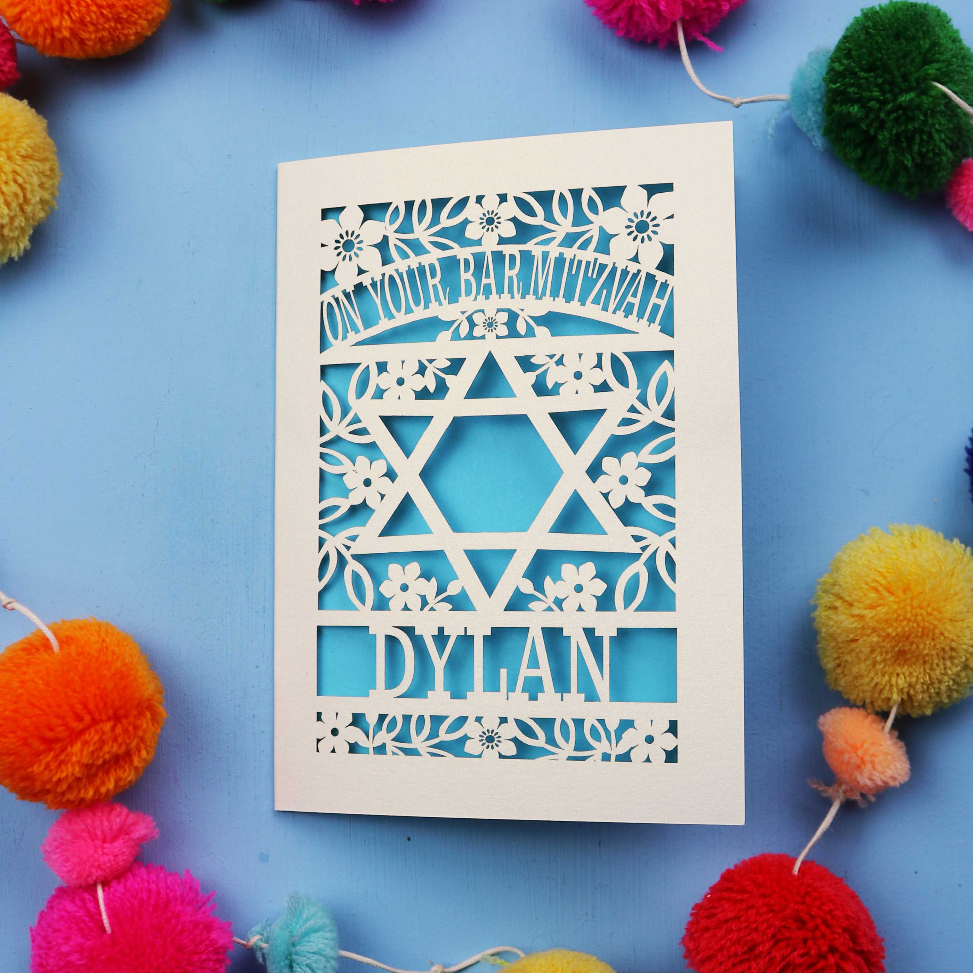 Special Bar Mitzvah Card with Star of David design and name 'Dylan' on a blue background with colourful pom-poms.