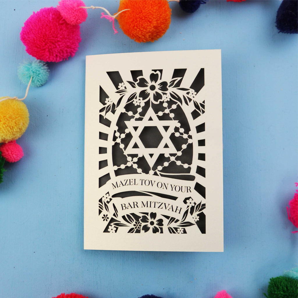 Laser Cut Bar Mitzvah card with Star of David design on a blue background with colourful pom-poms.