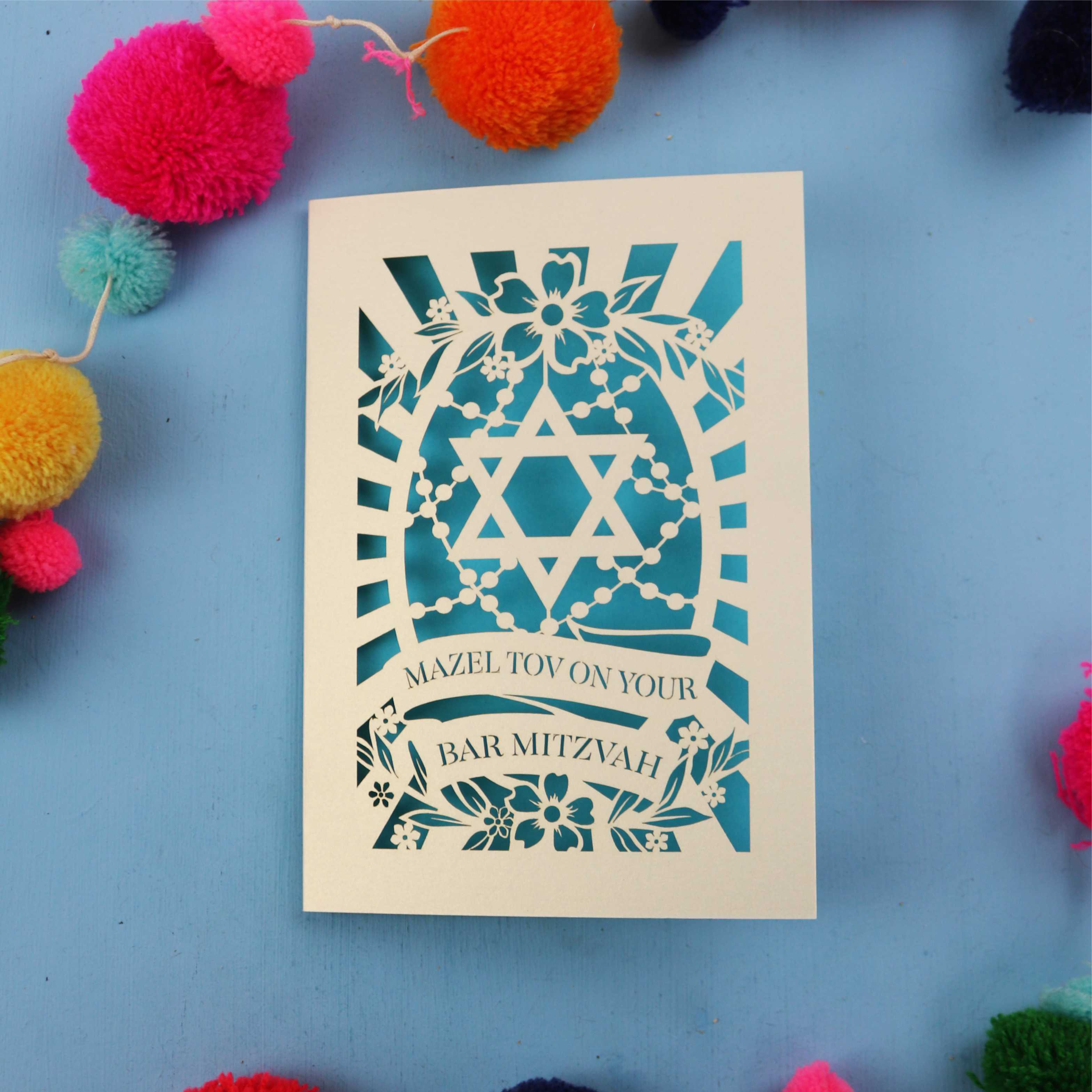 Laser Cut BarMitzvah card with Star of David design on a blue background with colourful pom-poms.