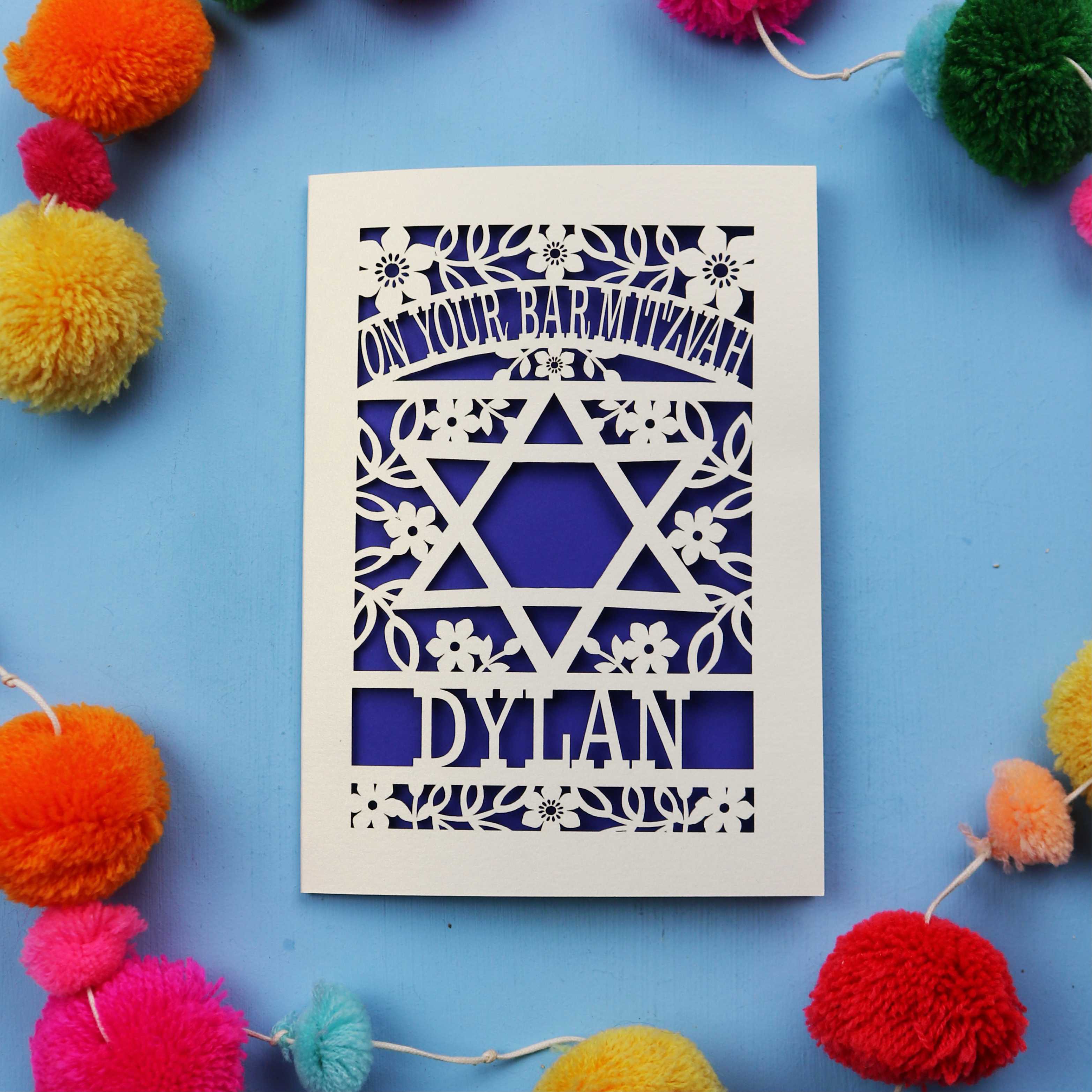 Unique Bar Mitzvah Card with Star of David design and name 'Dylan' on a blue background with colourful pom-poms.