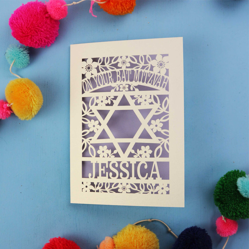 Personalised laser cut Bat Mitzvah card with Star of David design on a blue background with colourful pom-poms.