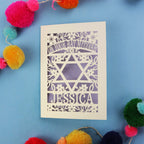 Personalised laser cut Bat Mitzvah card with Star of David design on a blue background with colourful pom-poms.