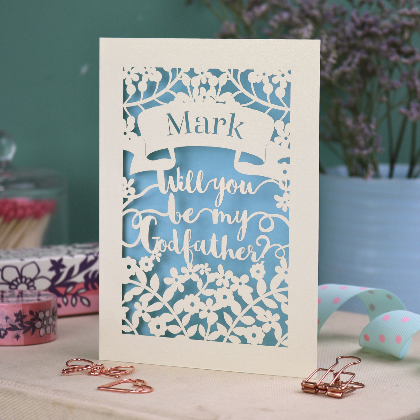 A laser cut Godfather card with 'Will you be my Godfather?' text and personalised with a name, on a decorative background