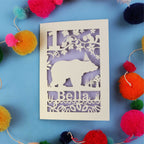 1st birthday Card with bear design and 'Bella' text on a blue background with colourful pom-poms.
