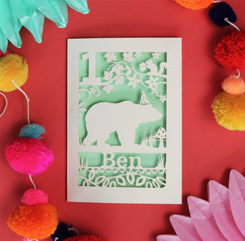 Personalised laser cut birthday card showing a bear in his party hat! Personalise with age and name. Laser cut from cream  card with a pale green insert.