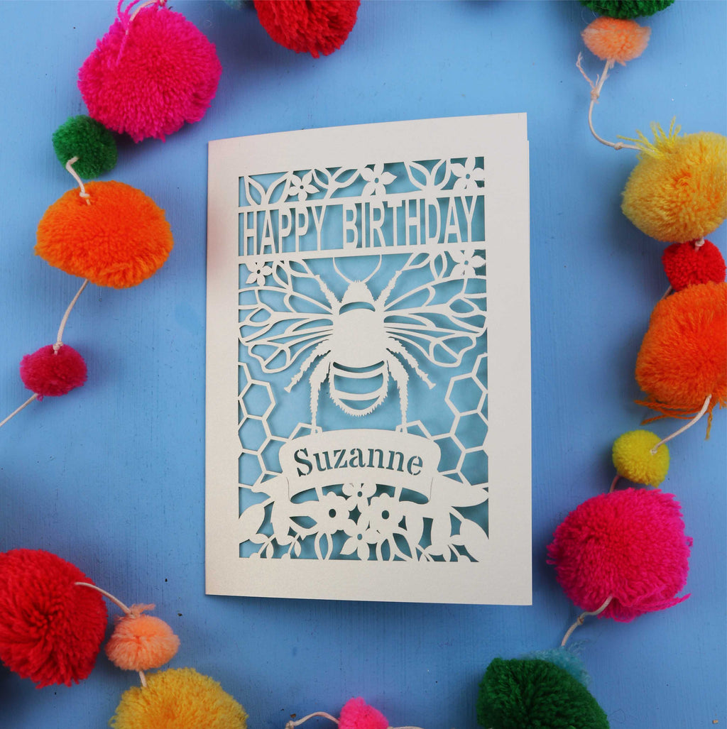 Birthday card with bee design and colourful pom-poms on a blue background