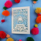 Birthday card with bee design and colourful pom-poms on a blue background