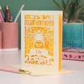 Laser-cut birthday card with cut out bee and honeycomb design and 'Happy 40th Birthday' text, personalised with the recipient's name in a banner underneath, on a desk.