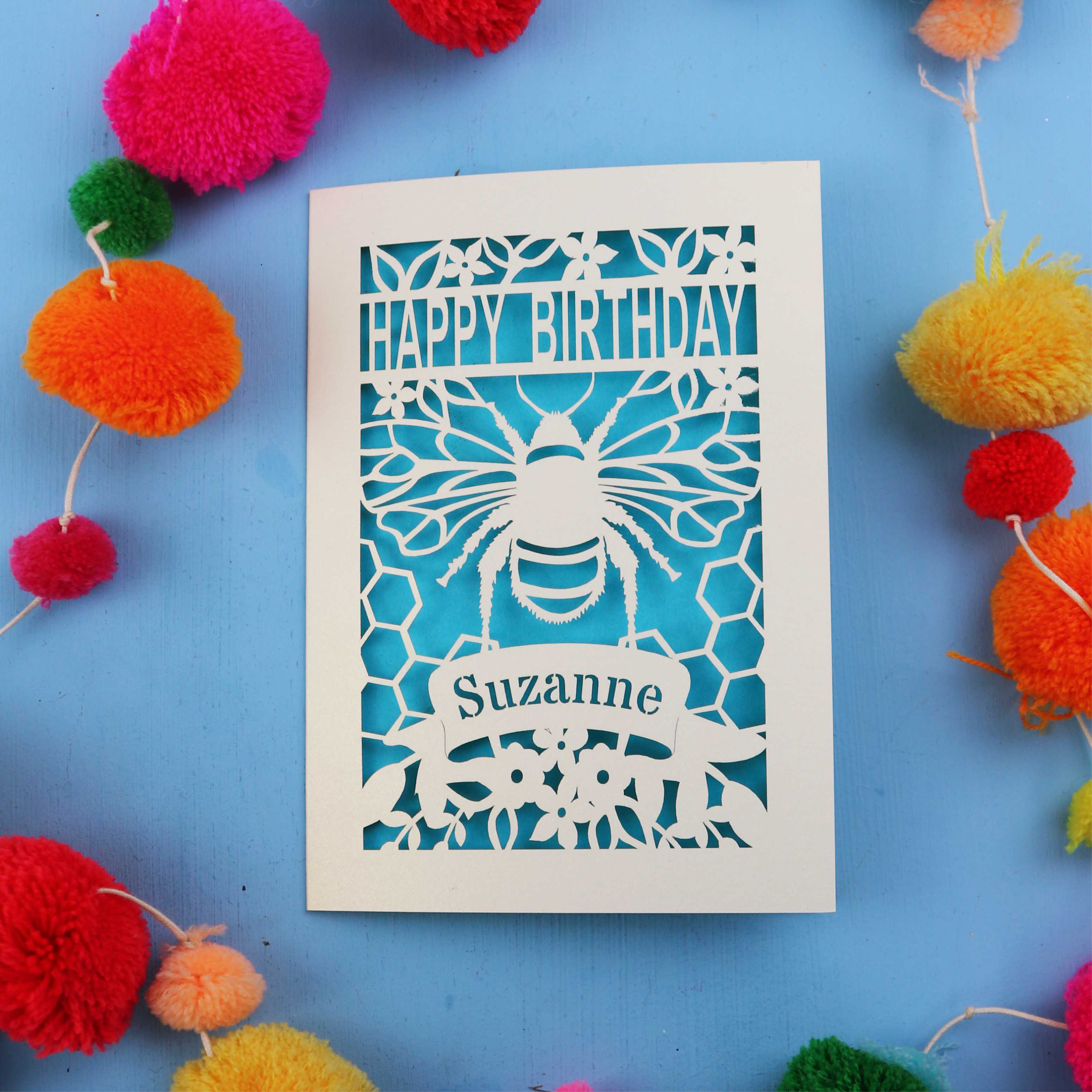 Personalised Birthday card with bee design and colourful pom-poms on a blue background