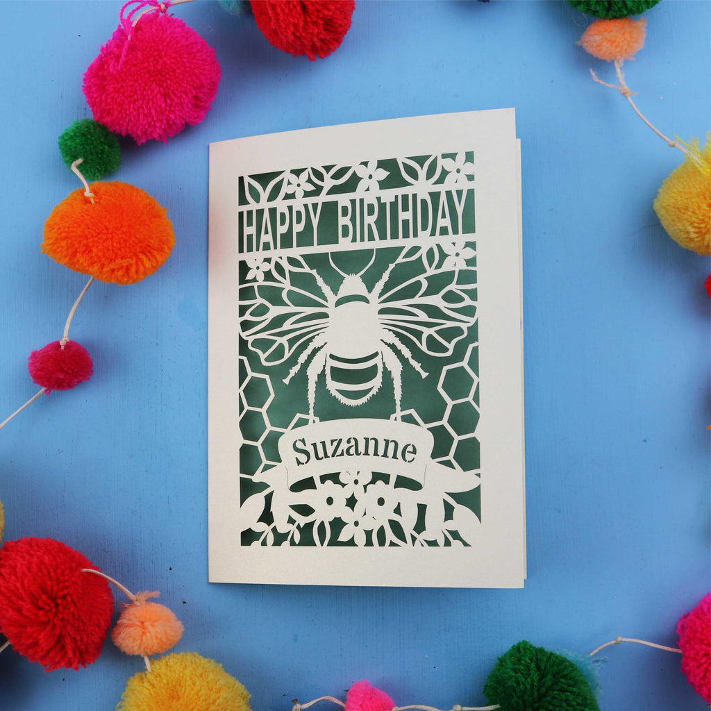 Birthday card with bee design and colourful pom-poms on a blue background