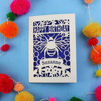 Birthday card with bee design and colourful pom-poms on a blue background