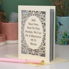 A custom laser-cut greeting card with a cream-colored frame and a silver inner panel featuring an ornate cream filigree design and a central oval placeholder that reads, 'Add Your Own Text To This Design. We Can Fit A Maximum Of 15 Words.