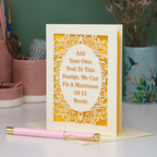 A bespoke laser cut personalised greeting card with a cream ornate filigree border and a yellow backing, displayed on a white surface with a pink pen in the foreground. The card features placeholder text that reads 'Add Your Own Text To This Design.