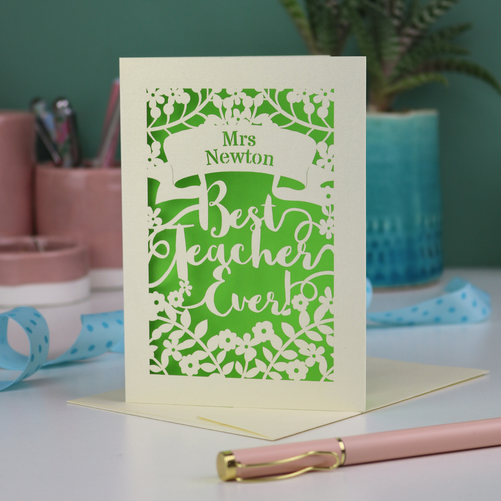 A cream laser cut card with floral design and the text "Mrs Newton. Best Teacher Ever!" Card has a bright green paper insert