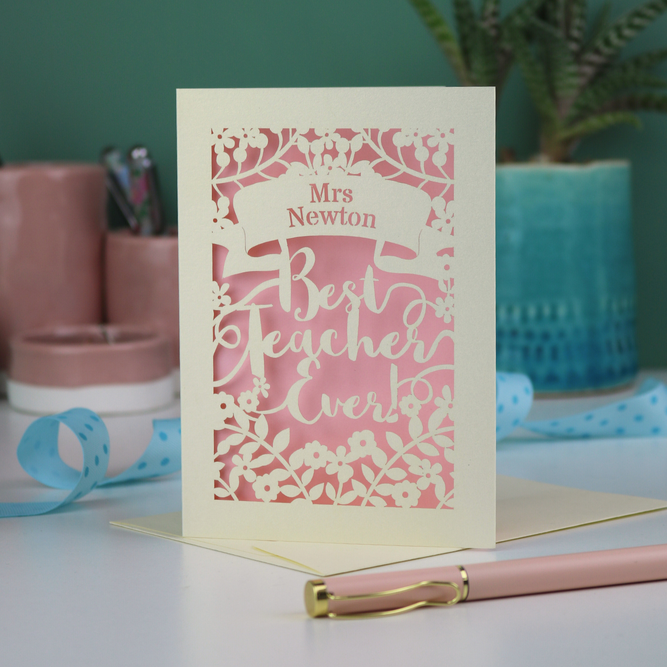 A cream laser cut card with floral design and the text "Mrs Newton. Best Teacher Ever!" Card has a light pink paper insert
