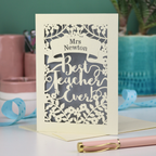A cream laser cut card with floral design and the text "Mrs Newton. Best Teacher Ever!" Card has a silver paper insert