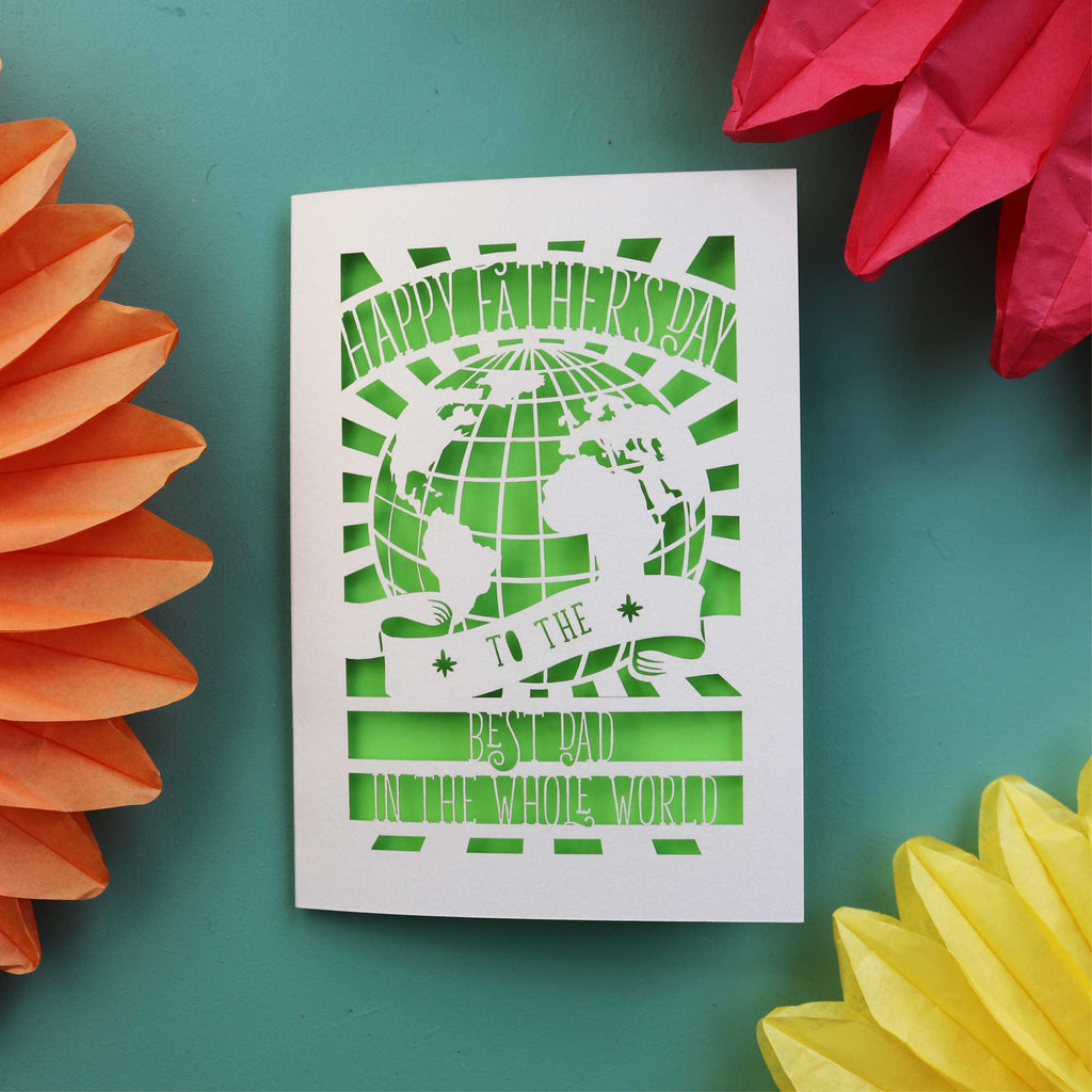 A paper cut Father's Day card with a cut out of the world and the words "Happy Fathers Day to the best dad in the whole world"
