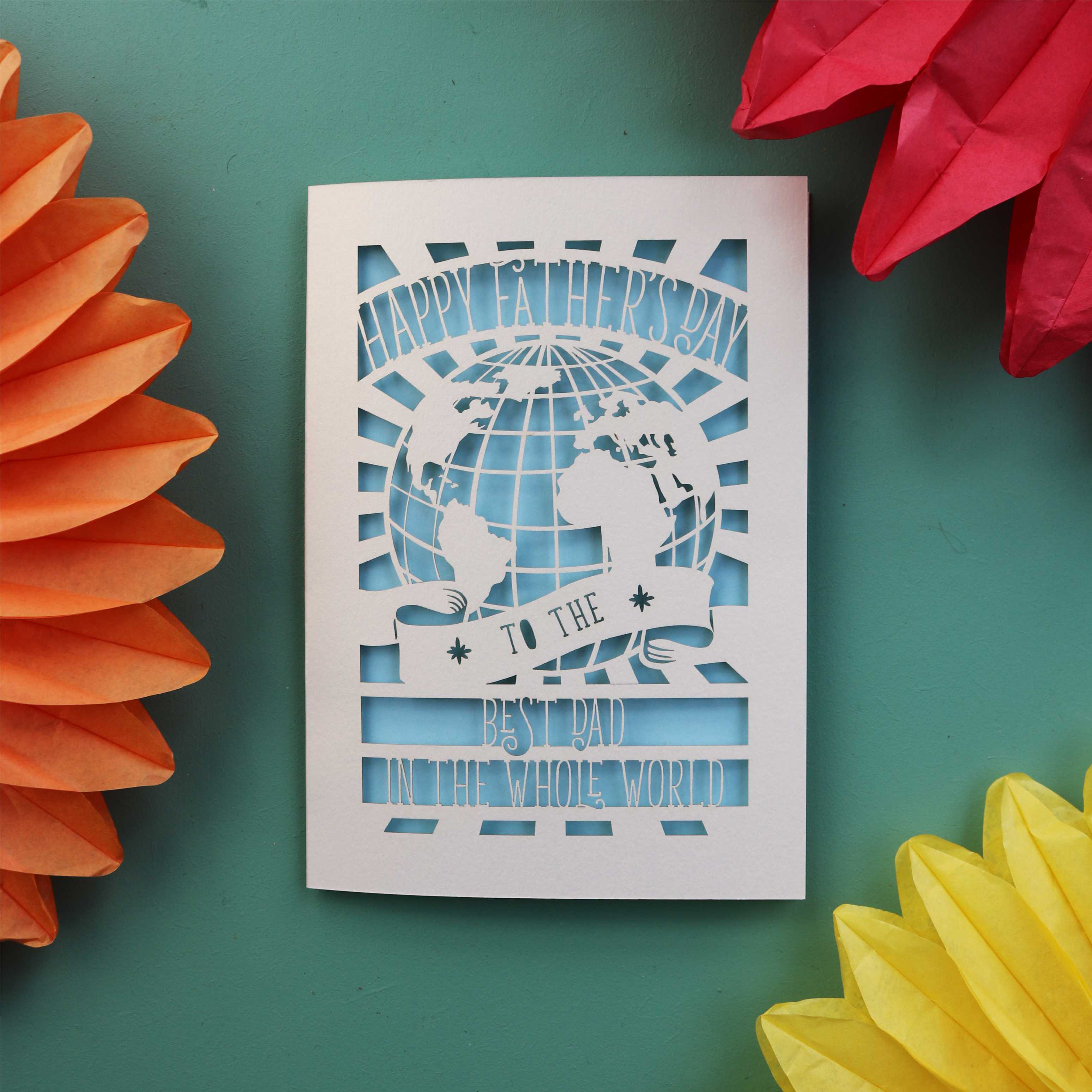 A unique Father's Day card with a cut out of the world and the words "Happy Fathers Day to the best dad in the whole world"