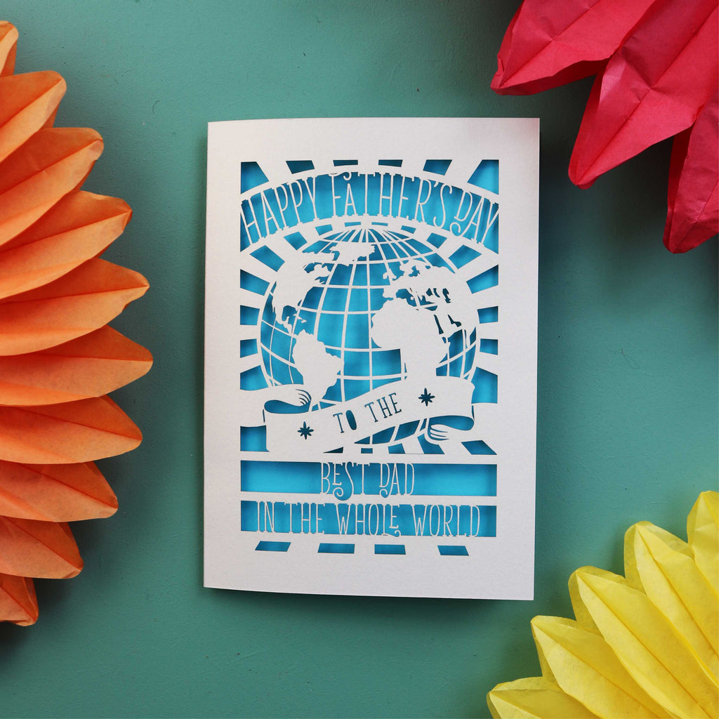 A laser cut Father's Day card with a cut out of the world and the words "Happy Fathers Day to the best dad in the whole world"