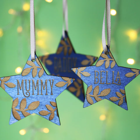 Personalised Christmas decorations in the shape of stars, painted blue and engraved with names - 