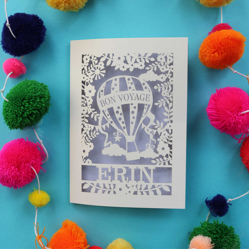 A personalised bon voyage card, laser cut from cream card with a lilac paper backing