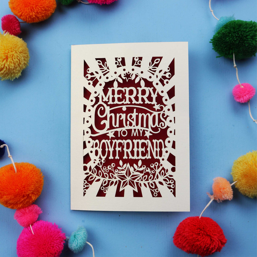 Laser cut Boyfriend Christmas card with 'Merry Christmas to my boyfriend' text on a blue background with colourful pom-poms.