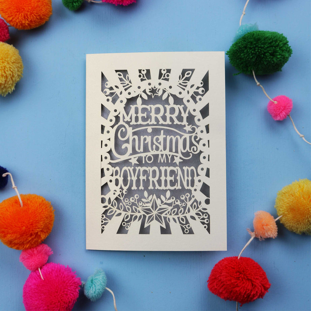 Decorative Boyfriend Christmas card with 'Merry Christmas to my boyfriend' text on a blue background with colourful pom-poms.
