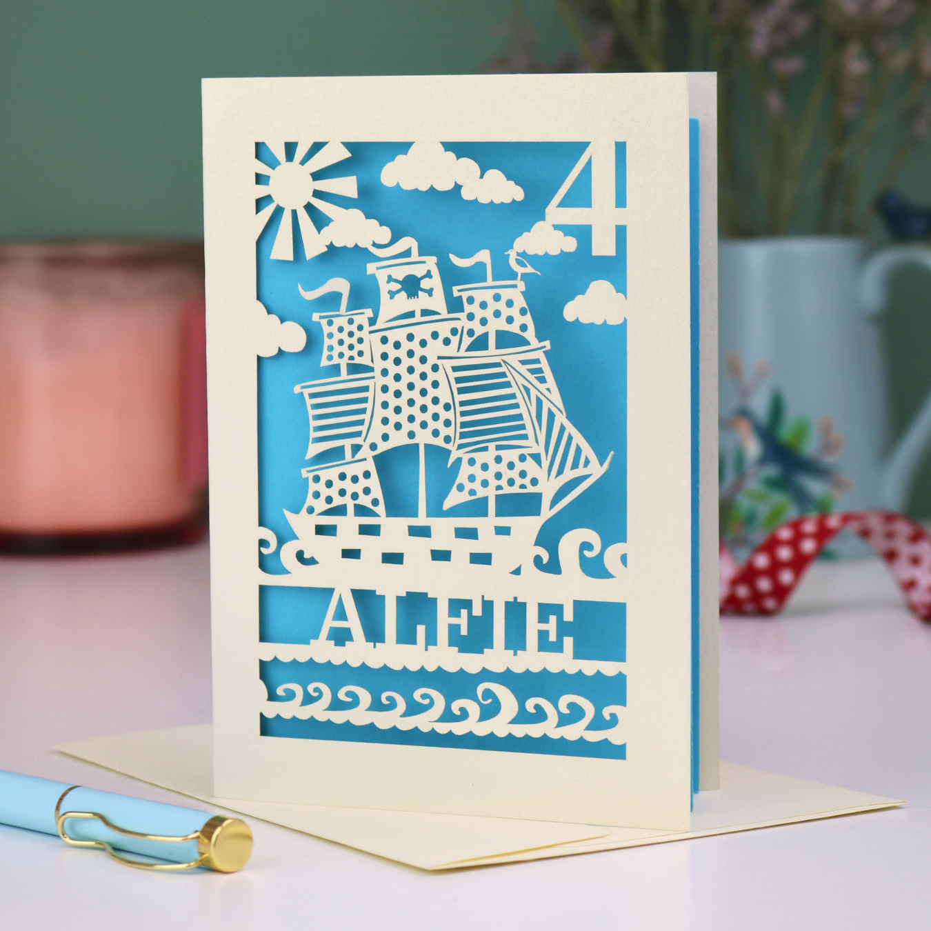 A laser cut boys birthday card with cut out pirate ship design and personalised with an age and name