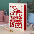 Laser cut Stepdad Card with personalized text, "John is the most awesome stepdad ever. Fact." on a table with decorative items