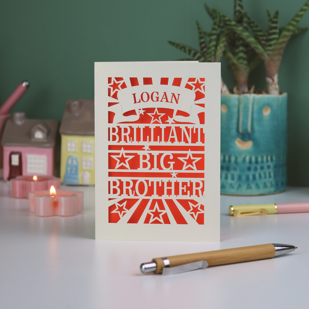 Card with 'Logan, Brilliant Big Brother' text on a table with decorative items.