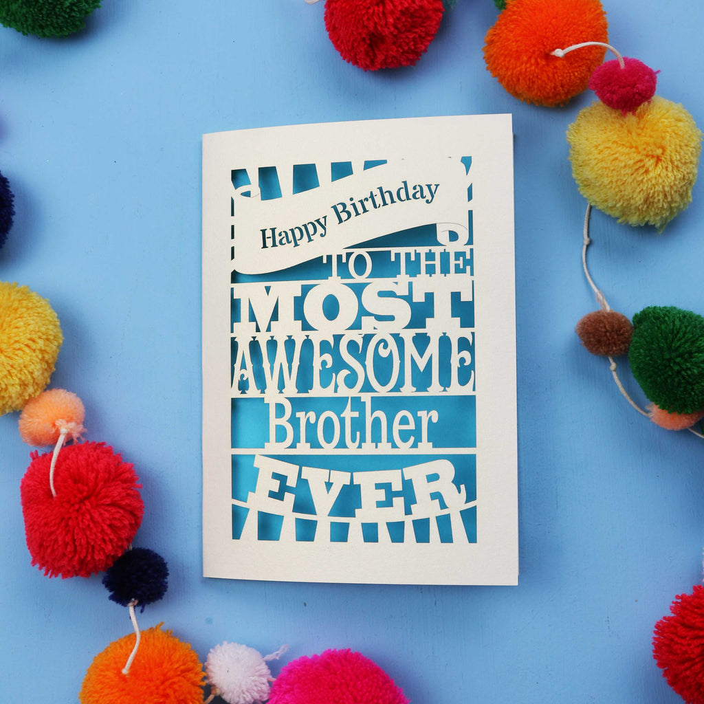 Laser cut brother Birthday card for the most awesome brother ever on a blue background with colourful pom-poms.