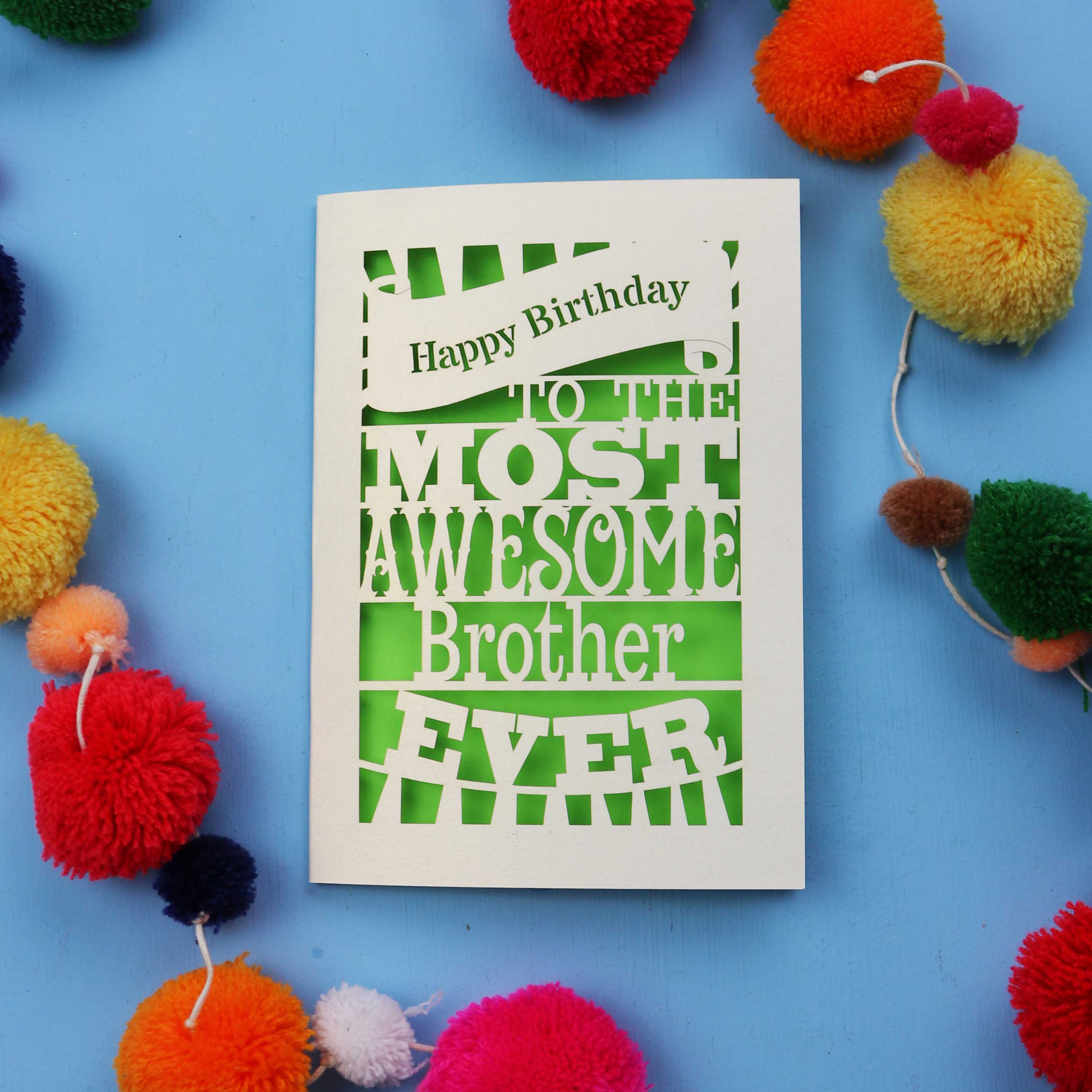 Laser cut brother Birthday card for the most awesome brother ever on a blue background with colourful pom-poms.
