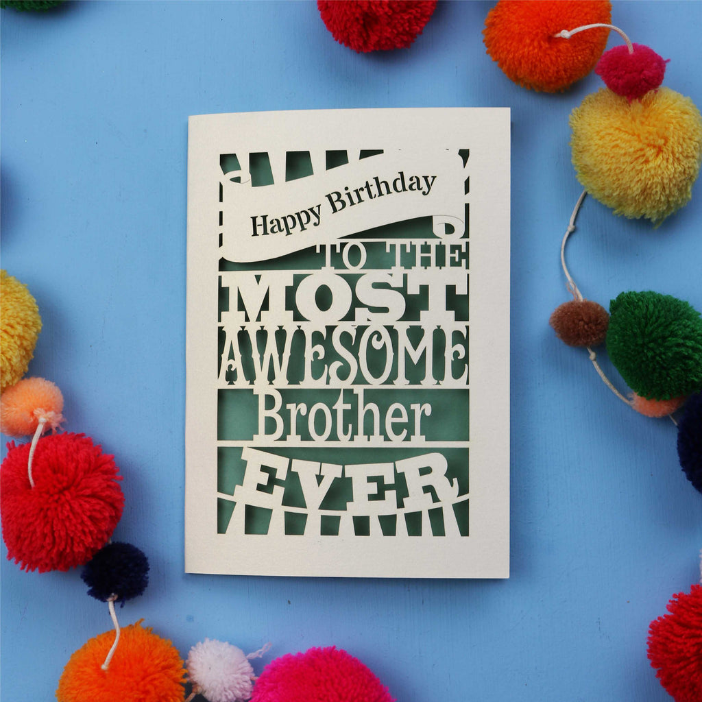 Laser cut brother Birthday card for the most awesome brother ever on a blue background with colourful pom-poms.