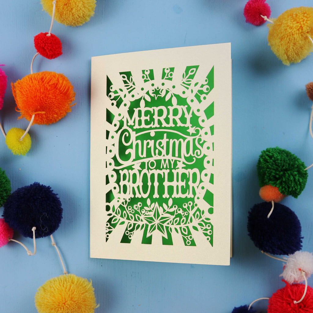 Brother Christmas card with 'Merry Christmas to my brother' text on a blue background with colourful pom-poms.