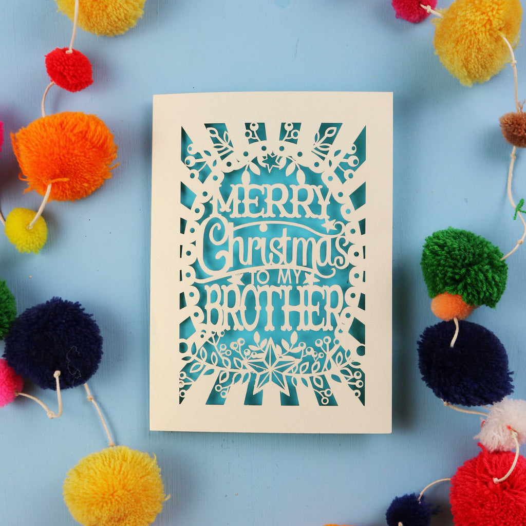 Brother Christmas card with 'Merry Christmas to my brother' text on a blue background with colourful pom-poms.
