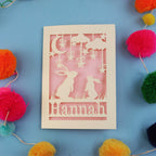 Decorative birthday card with cut-out rabbits and 'Hannah' text on a blue background with colourful pom-poms.