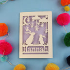 Decorative birthday card with cut-out rabbits and 'Hannah' text on a blue background with colourful pom-poms.