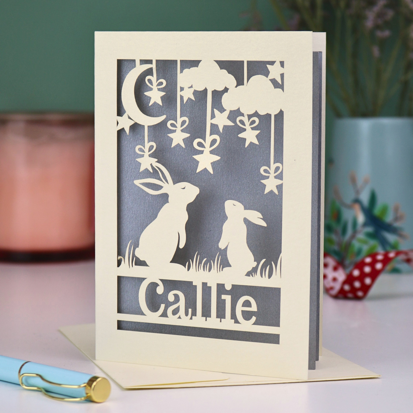 Special laser cut birthday card with cut-out rabbits and 'Callie' text on a light surface.