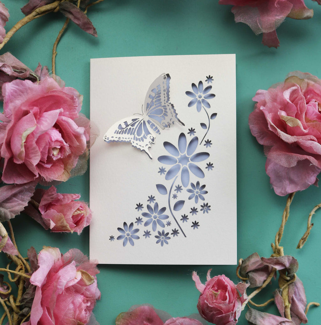 A papercut greetings card with a 3D butterfly and cut out flowers